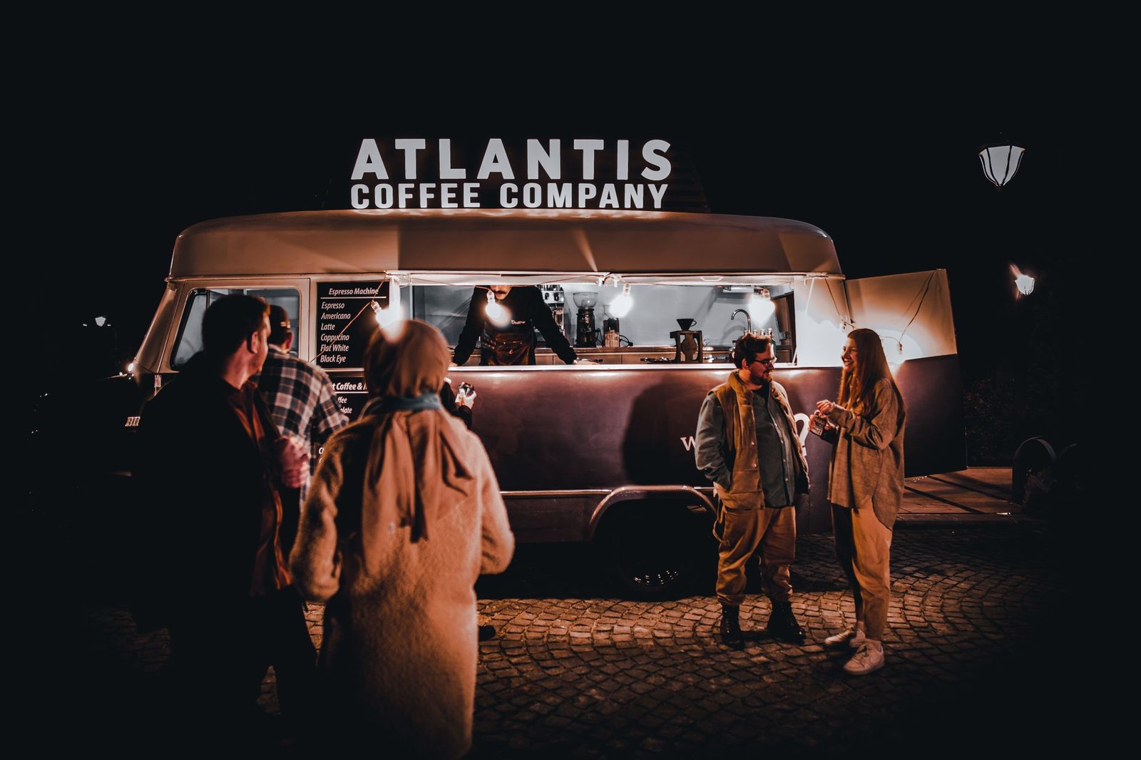 people standing outside of an atlantis coffee truck